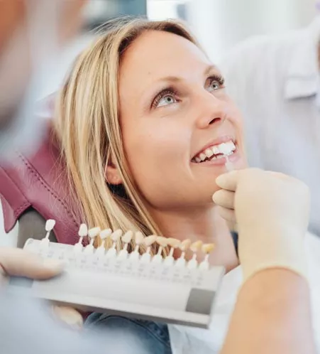 Holding shade guide up to woman's teeth